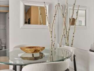 This dining area features a sleek glass-top table with comfortable upholstered chairs, perfect for intimate meals.