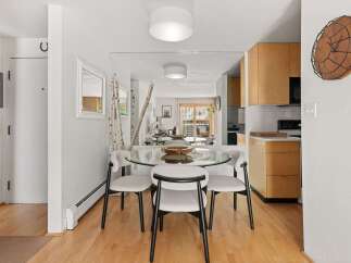 This dining area features a sleek glass-top dining table with four modern chairs, perfect for intimate meals.