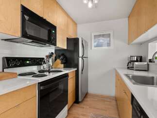 Discover this charming kitchen featuring sleek, light wood cabinetry that complements the modern white countertops.