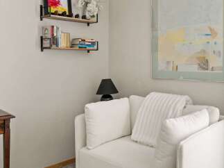 This cozy reading nook features a plush white sofa adorned with soft throw pillows and a textured blanket, perfect for relaxing with a good book.