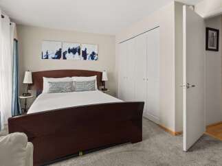 This inviting bedroom features a comfortable queen-size bed with a dark wood sleigh frame, adorned with crisp white linens and decorative pillows.