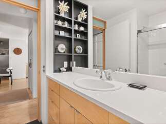 This modern bathroom features a sleek vanity with light wood cabinetry and a white quartz countertop.