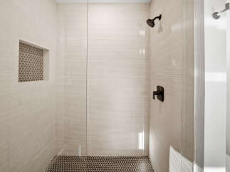 Experience modern luxury in this sleek shower featuring textured beige tile walls and a built-in niche with mosaic tile.