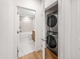 This modern apartment features a sleek bathroom with a bathtub, toilet, and a wooden vanity, all complemented by elegant marble flooring.