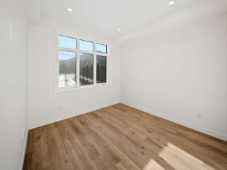 Step into this bright and airy room, featuring a large window that floods the space with natural light and offers scenic views of the surrounding mountains and modern townhouses.