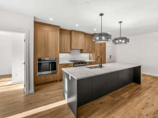 Experience modern luxury in this stunning kitchen, featuring sleek, dark cabinetry and a spacious island topped with elegant marble.