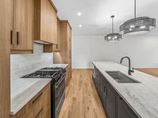 Experience modern luxury in this stunning kitchen, featuring sleek wooden cabinetry and elegant marble countertops.