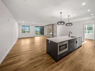 Experience modern living in this spacious open-concept home featuring a sleek kitchen island with a built-in microwave and sink.