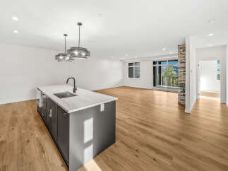 Experience modern living in this spacious open-concept home, featuring a sleek kitchen island with a waterfall countertop and a contemporary faucet.
