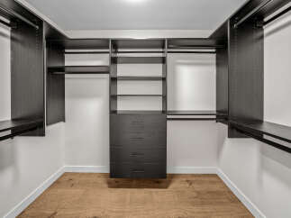 This spacious walk-in closet features a custom dark wood shelving system, offering ample storage for clothing and accessories.