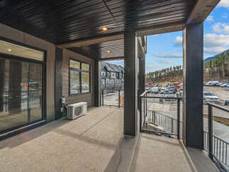 Enjoy the outdoors from this spacious balcony, featuring a modern dark wood ceiling with integrated lighting and a sleek glass railing.