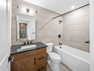 This modern bathroom features a sleek vanity with a dark countertop and a white undermount sink, complemented by black fixtures.