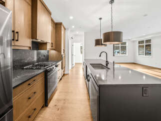 Experience modern living in this stunning kitchen featuring sleek wooden cabinetry and a spacious island with a built-in sink.