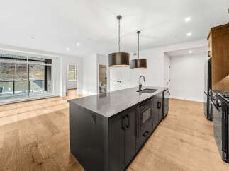 Experience modern living in this stunning kitchen featuring a sleek dark island with a built-in microwave and a sophisticated stone countertop.