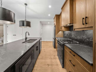 Experience modern luxury in this stunning kitchen, featuring a sleek island with a waterfall countertop and a deep undermount sink.