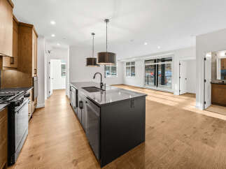 Experience modern living in this stunning kitchen featuring sleek dark cabinetry, a large island with a sink, and a professional-grade gas range.