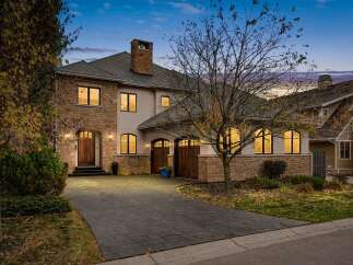 Experience luxury living in this stunning stone and stucco home, featuring a grand arched entryway and multiple garage bays.