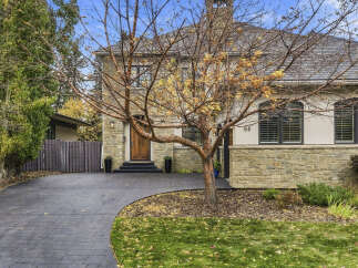 Welcome to this stunning stone-clad home, featuring a charming wooden door and elegant arched windows.