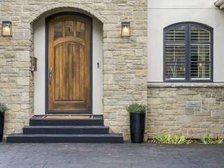 Step into luxury with this stunning home featuring a grand arched wooden door, perfect for welcoming guests.