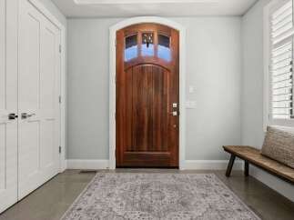 Step into a welcoming entryway featuring a stunning arched wooden front door with glass panes, offering a glimpse of the outdoors.