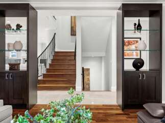 Step into a grand entryway featuring a stunning wooden staircase with a wrought-iron railing, perfect for welcoming guests.