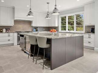 This stunning modern kitchen boasts a large central island with a granite countertop, perfect for meal preparation and casual dining.