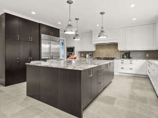 This spacious kitchen boasts a large island with a granite countertop, perfect for meal preparation and casual dining.