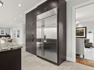 Experience luxury in this modern kitchen featuring a sleek, built-in stainless steel refrigerator seamlessly integrated with dark wood cabinetry.