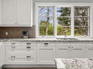This stunning kitchen boasts pristine white cabinetry complemented by elegant granite countertops, offering both style and ample workspace.