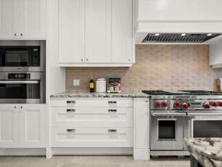 This stunning kitchen boasts a professional-grade stainless steel range with red knobs, perfect for the home chef.
