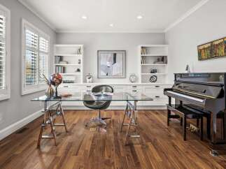 This elegant home office features a sleek glass-top desk with a leather executive chair, perfect for productivity.