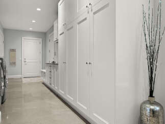 This spacious laundry room features ample white cabinetry for storage, complemented by a granite countertop and a built-in bench.