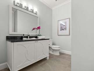 This elegant bathroom features a white vanity with a black granite countertop, complemented by a modern vessel sink and a sleek faucet.
