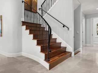 Experience elegance and sophistication with this stunning staircase, featuring rich hardwood treads and a sleek black wrought iron railing.