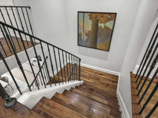 Ascend in style with this elegant staircase, featuring rich hardwood treads and a classic black wrought iron railing.