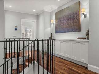 Ascend the elegant staircase with its ornate black railing, leading to a beautifully appointed hallway.