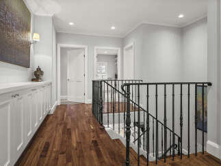 Step into this elegant hallway featuring rich hardwood floors that gleam under recessed lighting.