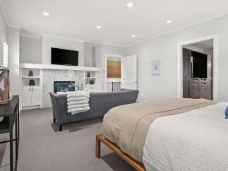 Experience luxury living in this spacious master suite, featuring a cozy fireplace and a mounted television for ultimate relaxation.