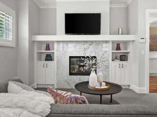 Experience modern living in this beautifully appointed living room, featuring a sleek fireplace with a marble surround and a large flat-screen TV mounted above.