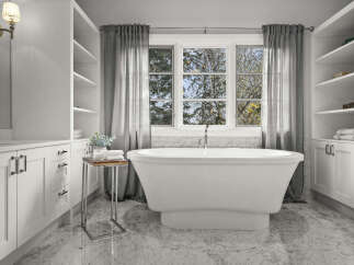 Indulge in luxury with this stunning bathroom featuring a freestanding soaking tub positioned perfectly under a large window, offering serene views of nature.
