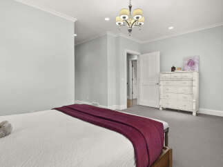 This inviting bedroom features a plush king-sized bed adorned with a rich burgundy throw, perfect for cozy evenings.