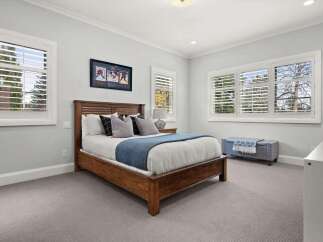 This inviting bedroom features a warm wooden bed frame adorned with crisp white linens and a cozy blue throw.