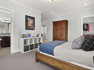This charming bedroom features a comfortable bed with a blue knit throw and decorative pillows, perfect for relaxation.