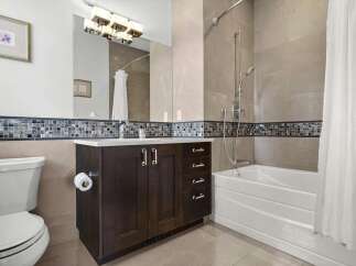 This modern bathroom features a sleek dark wood vanity with ample storage and a white countertop.