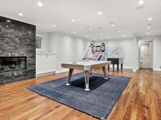 This spacious basement recreation room offers endless entertainment possibilities, featuring a modern pool table, a basketball arcade game, and a foosball table.