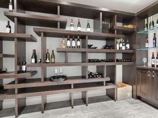This stunning wine cellar features a custom-built, dark wood shelving unit designed to elegantly display a vast collection of wine bottles.