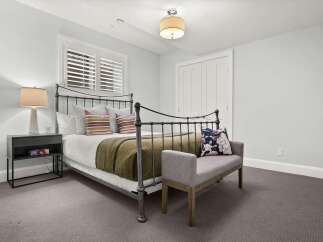 This charming bedroom features a classic wrought iron bed, complemented by a cozy green throw and striped accent pillows.