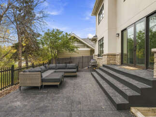 Enjoy outdoor living with this spacious patio featuring a comfortable sectional sofa and a grill, perfect for entertaining guests.