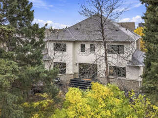 Nestled amidst mature trees, this stunning residence offers a private oasis with vibrant fall foliage.
