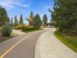 Discover this beautifully landscaped property featuring a paved walking path with a yellow dividing line, perfect for morning jogs or evening strolls.
